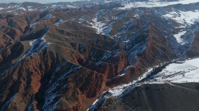 Drone footage of the Jety Oguz Gorge and the Seven Bulls red sandstone cliffs with snow-covered ridges and valleys, Issyk-Kul Region, Kyrgyzstan