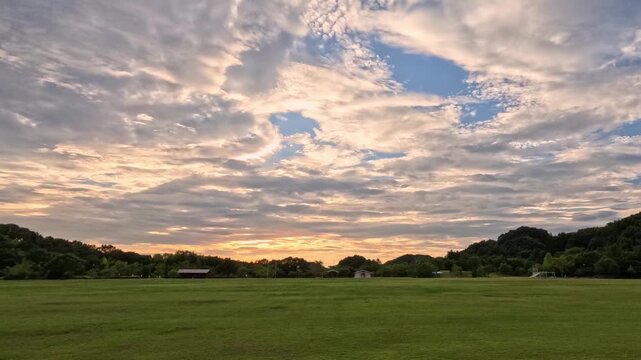 美しい夕焼けのタイムラプス、緑に包まれた夏の運動公園