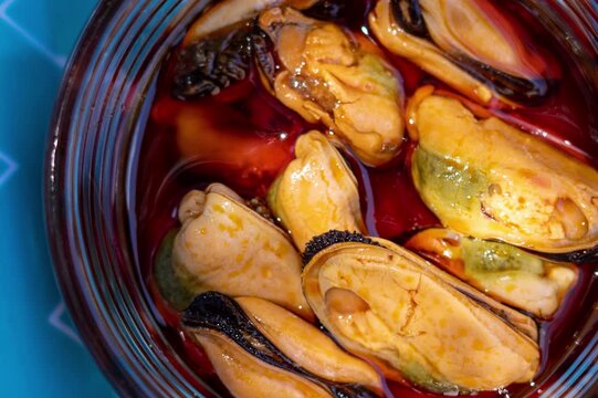 Close-up of mussels in red marinade jar