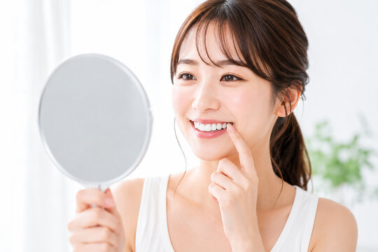 鏡で白い歯を確認する笑顔の女性