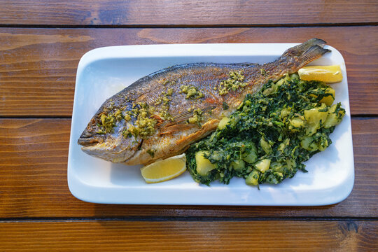 Balkan cuisine. Grilled fish of  sea bream with green leafy vegetables