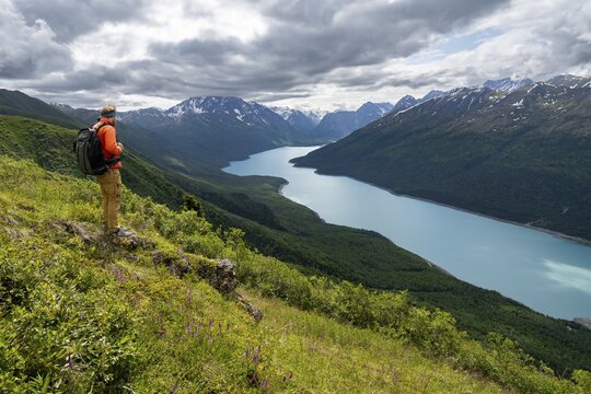 Mountaineer enjoys views of blue lake and mountains on Twin Peaks Trail, Eklutna Lake, Chugach Mountains, Chugach State Park, Alaska, USA