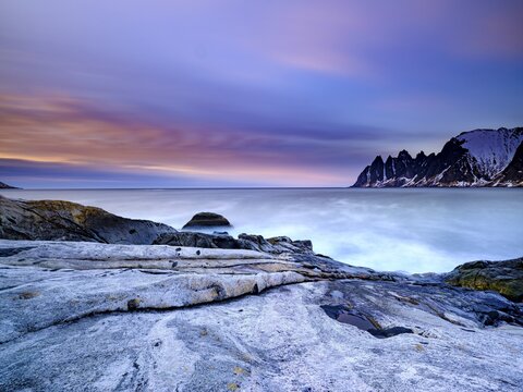 Granite beach, Devils Teeth mountain peak behind, Okshornan mountain range, Tungeneset, Senja Island, Troms, Norway