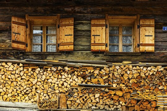 Old windows with shutters on an old farmhouse, firewood piled up in front, mountain village of Ayer, Val d'Anniviers, Valais Alps, Canton Valais, Switzerland