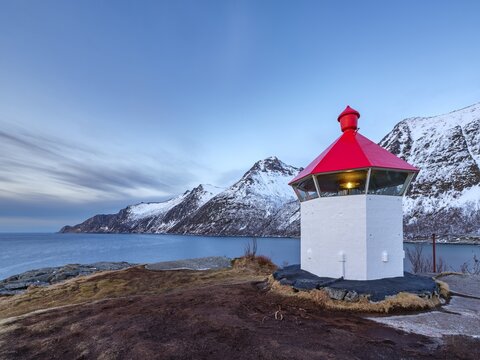 Small lighthouse at the end of Hus&oslash;y island with a view across the fjord to the sea, Senja island, Troms, Norway