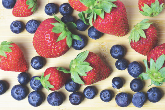 Zenith view,  strawberries and blueberries on a bamboo board.