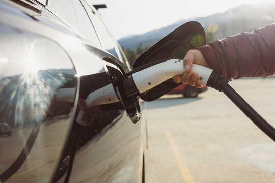 Person plugging in an electric vehicle to charge