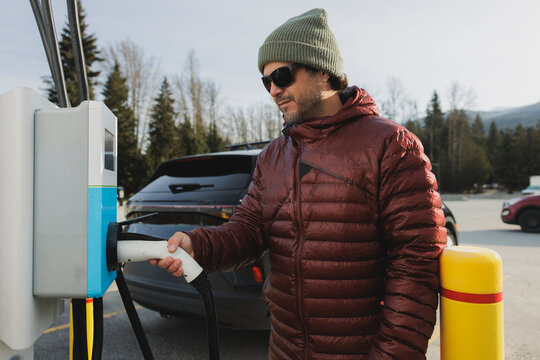 Man plugging in his electric vehicle outdoors