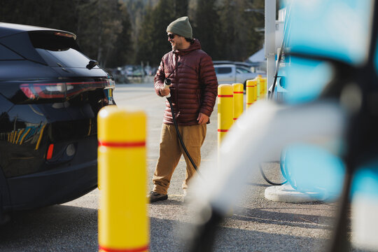 Man charges his black electric SUV at a charging station