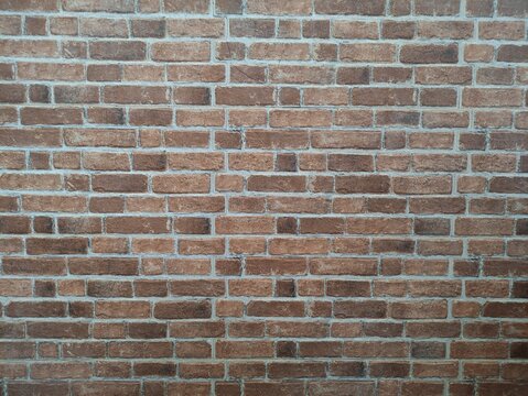 Realistic brown brick wall texture with grey mortar lines for background design.