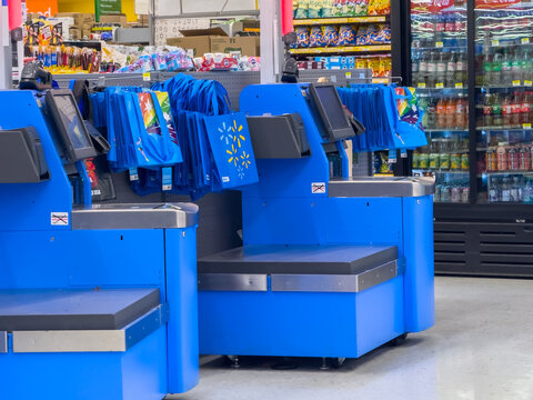 Calgary, Alberta, Canada. June 5, 2026. Medium shot of blue self-checkout kiosks and reusable shopping bags inside a Walmart store.