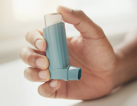 Close-up of an inhaler in hand used for respiratory support in a simple healthcare setting.