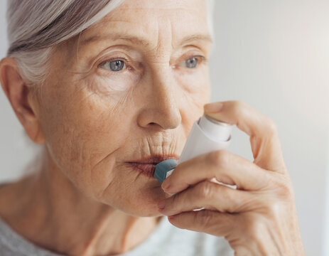 An elderly female patient managing a chronic respiratory condition using a prescribed metered-dose inhaler during a medical treatment session