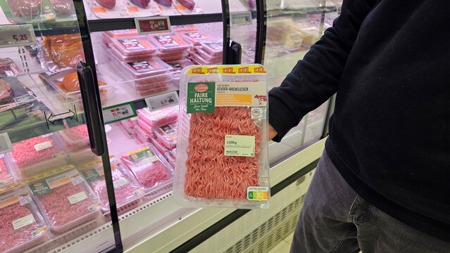 Shopper holding package of ground beef displaying animal welfare label