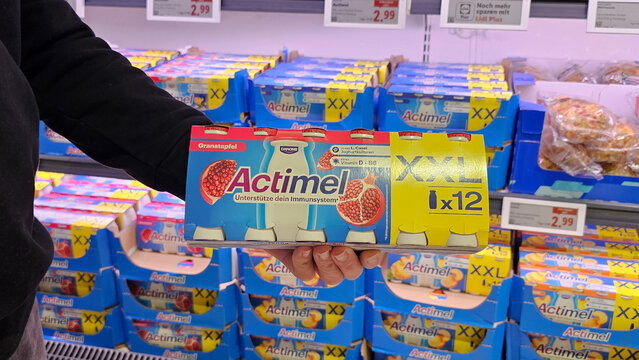 Hand holding actimel pomegranate yogurt drink in supermarket