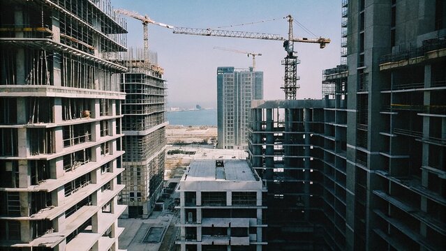 Aerial view of a skyscrapers under construction with huge cranes in Dubai marina. Blue sky on a background. United Arab Emirates

