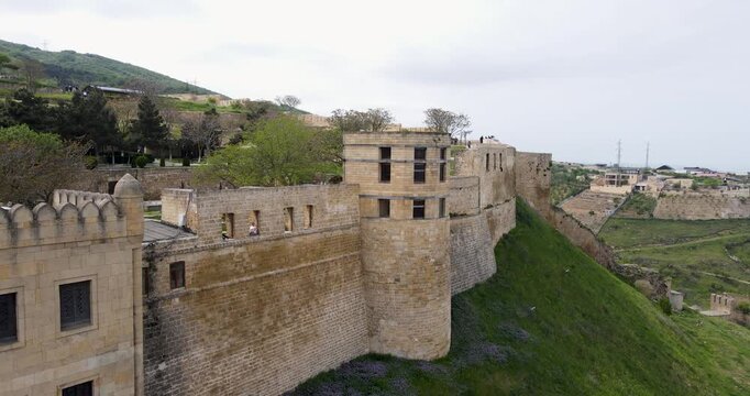 Cinematic aerial orbit shot of the ancient stone watchtower and battlements of Naryn-Kala fortress in Derbent
