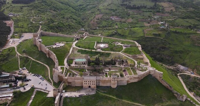 Aerial drone forward flight over the ancient Naryn-Kala fortress complex on mountain green hills in Derbent