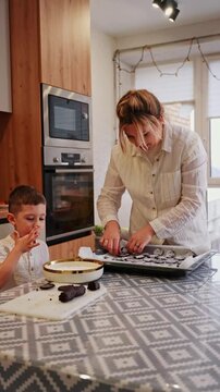 Mother and son baking cookies together in kitchen
