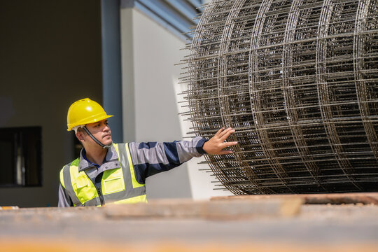 Asian workers inspect the wire mesh on the truck. ,  Construction worker in a yellow hard hat