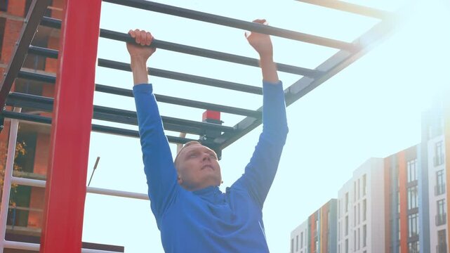 Man doing pull-up on outdoor monkey bars in city park