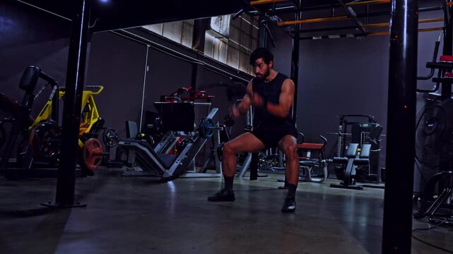 Man gym exercise battle rope fitness workout athlete strength training indoor dumbbell bench squat medicine ball dark fitness center focused male athlete building power equipment