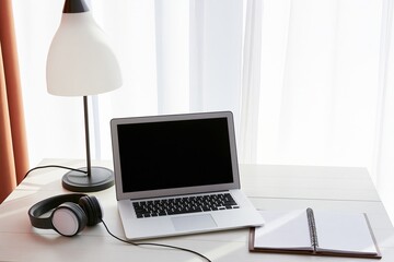 Fototapeta premium Laptop workspace with headphones and desk lamp by window