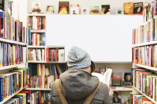 Young reader standing between library bookshelves