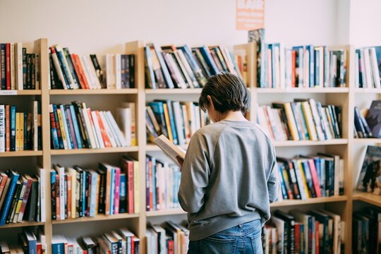 Young reader browsing books in modern library aisle