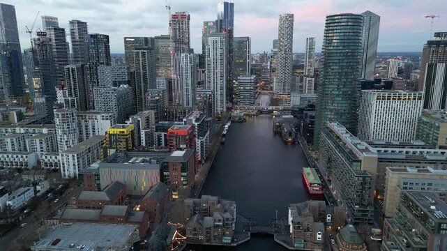 Aerial drone shot of Canary Wharf skyscrapers and Millwall Inner Dock in London at dusk.