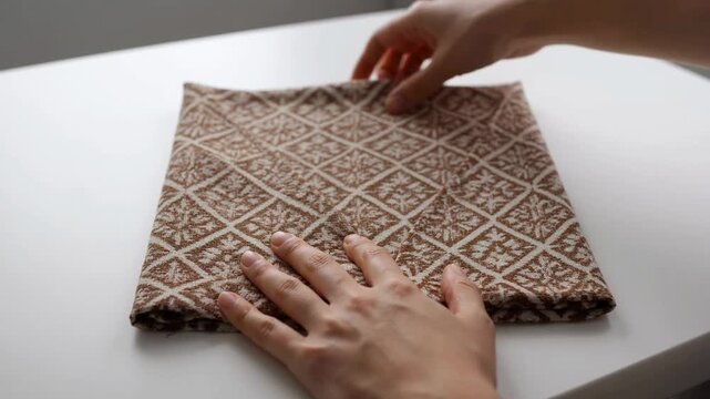 Hands working with brown patterned fabric.