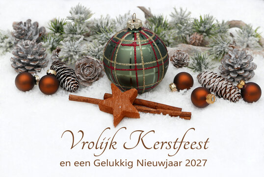 Decoration with a green Christmas bauble, cinnamon sticks, a star, and snow-covered fir branches. With the Dutch text "Vrolijk Kerstfeest en een Gelukkig Nieuwjaar 2027" 
