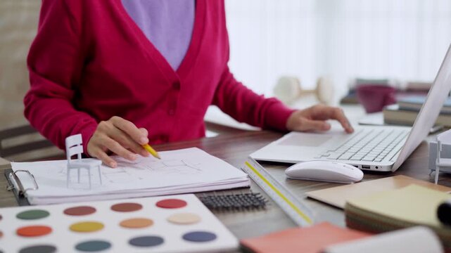 furniture designer using laptop computer selecting color palette sample materials planning interior project at creative studio workspace home office desk