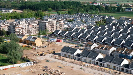 Obraz premium Aerial view of a newly built estate of modern single-family houses arranged in rows on the outskirts of Warsaw near the village of Kreczki, suburban expansion, the real estates.