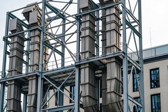 Industrial heritage architecture at the EC1 complex in Lodz, showing a close-up of a monumental steel framework structure with vertical ventilation ducts, metal walkways, and safety railings against a