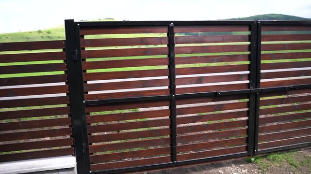 Slow pan shot, new ,painted pine wood horizontal fence, main gate with 1 inch gaps between the pine boards.