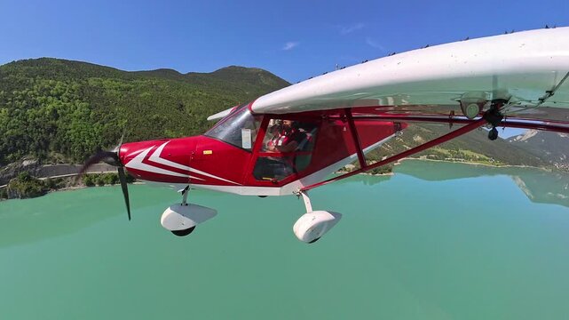 aerial footage, dynamic selfportrait of light airplane flying over turquoise lake of castillon in provence under blue sky