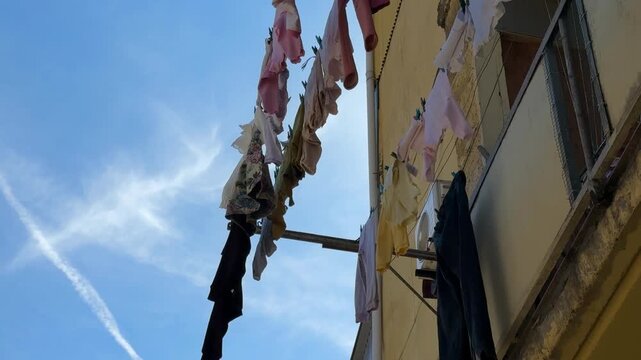 Laundry drying on clotheslines against bright blue sky, depicting urban lifestyle and sustainability