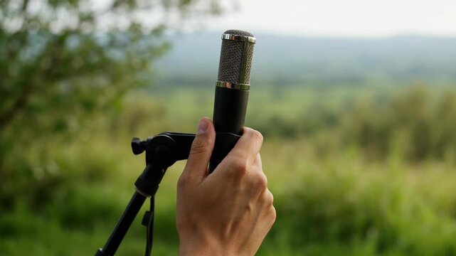 A hand holding a monocular in a natural setting.