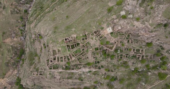 Epic top down aerial zoom out shot of the ancient stone ruins of the abandoned village terraced on mountain cliffs in Kahib, Dagestan