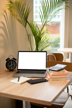 Modern minimalist workspace on a wooden desk featuring a blank screen laptop