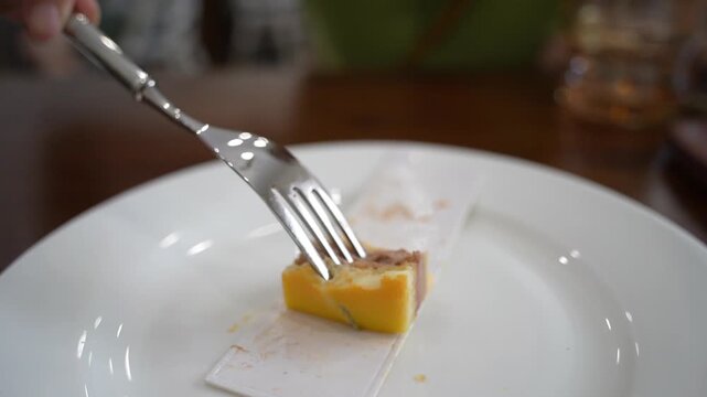 Eating pomelo mousse cake on wooden table, by using a silver fork