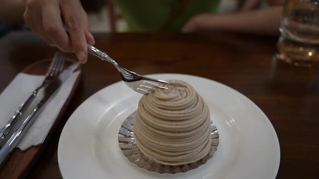 Eating Mont Blanc  cake on wooden table with a silver fork