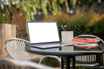 Fototapeta premium Laptop Mockup with Blank Screen and Stationery on Outdoor Table in Green Garden