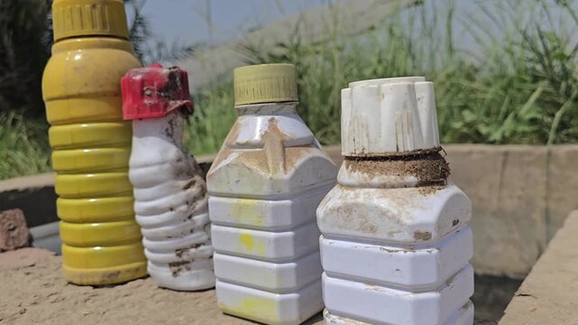 Pesticide plastic bottles on farm, agricultural chemical containers for crop protection, toxic herbicide and fertilizer packaging in rural setting