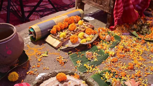 Close-up footage of a traditional Hindu puja setup featuring sacred offerings, marigold flowers, banana leaves, earthen pot, and ritual materials after a havan ceremony