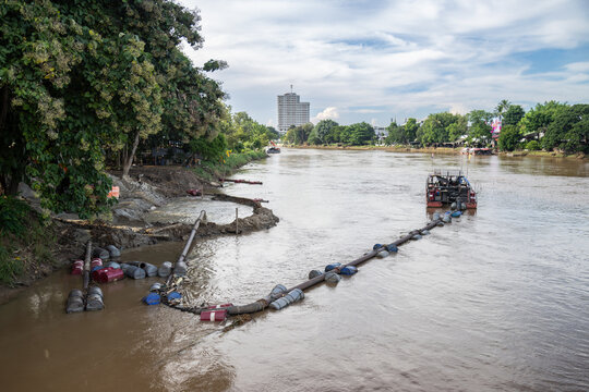 Dredging operations are underway on the Ping River in Chiang Mai, Thailand, to remove sediment and debris. A barge with pumps and floating pipes are visible.