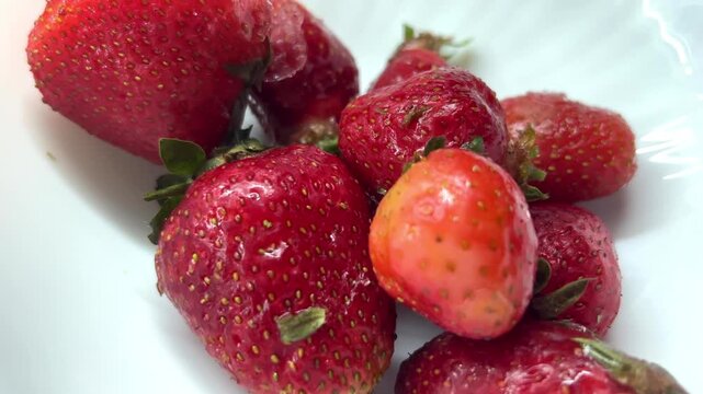 Strawberries are placed in a bowl on a table. These strawberries look ripe and ready to eat for a snack or dessert option