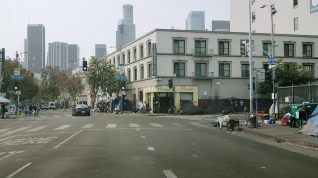 Skid row street scene with homeless tents and city skyline in downtown Los Angeles California.