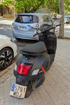 Vista trasera de moto scooter estilo retro Vespa GTS Super con parabrisas, estacionada en Madrid, Espa&ntilde;a, 26 de abril de 2026